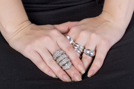 Closeup of the hands of a woman wearing multiple rings on her fingers with carefully manicured fingernails