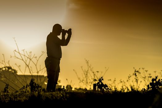 Silhouette of a standing photographer in a landscape at sunset