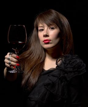 Young woman with red wine from a glass, on black