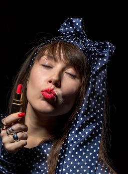 Sexy sensual woman applying red lipstick to her lips against a dark background