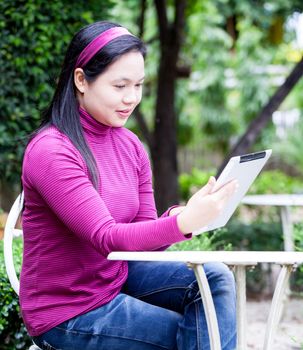 Smiling young woman using tablet PC for working in garden