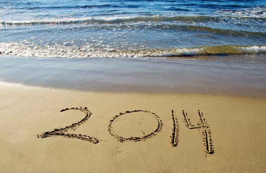 2014 new year written in sand on the beach