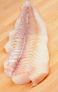 Raw Fresh Cod Fish Fillet closeup on Wooden Cutting Board