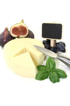 Piece of cheese with figs, grapes, basil and blackboard