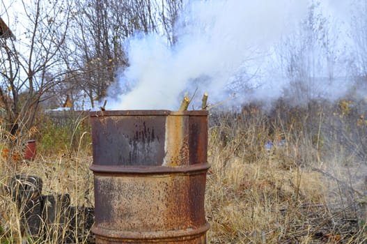 Smoke from a barrel with garbage on a country site