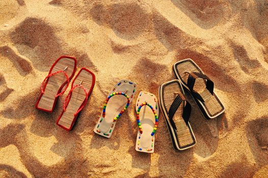 Three pair of beach sandals on the sandy beach