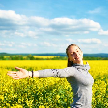 Girl with outstretched arms at colza field