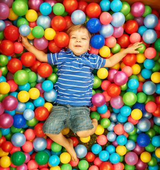 Happy child playing at colorful plastic balls playground high view