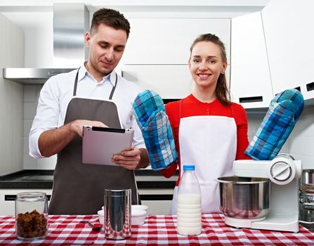 Couple at kitchen cooking together with tablet pc