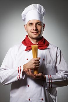 Male chef holding pasta against grey background