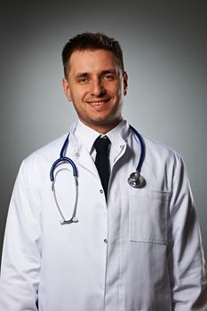 Medical doctor with stethoscope portrait against grey background 