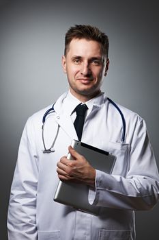 Medical doctor with tablet pc portrait against grey background 