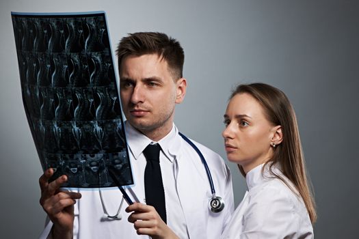 Medical doctors team with MRI spinal scan portrait against grey background 