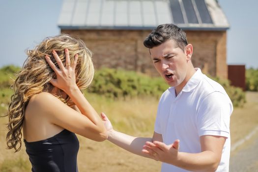 Angry man shouting and beautiful girl cover her ears in a hard quarrel