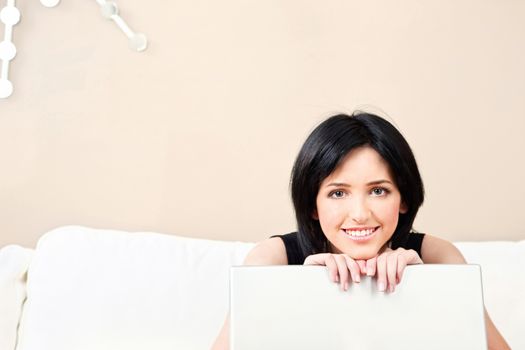 Pretty girl on white sofa with laptop at home