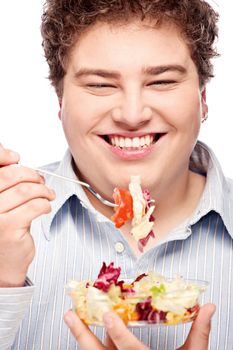 Happy young chubby man eating fresh salad with fork, isolate on white