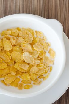 top view corn flake  with fresh  milk in white bowl 