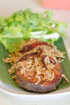 Fried pickled fish , fried onion  and fried chili served  with fresh vegetable over banana leaf on dish