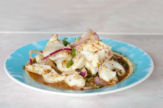 spicy seafood salad with squid and chili sauce on blue dish