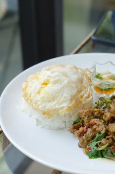 close up steamed rice and fried egg , served with  stir fried minced pork with chili , sweet basil on dish