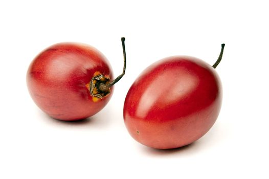 Two whole ripe and juicy tamarillo on white background