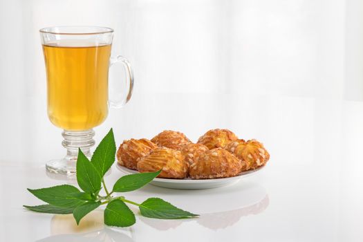 Tea in a glass cup, fresh mint leaves and tasty cookies.
