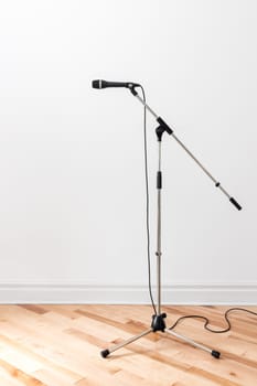 Dynamic microphone on a stand, in an empty room.