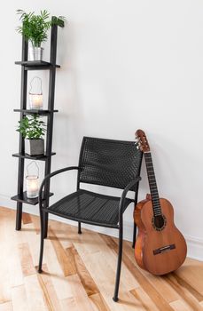 Room with simple black furniture, plants and classical guitar.