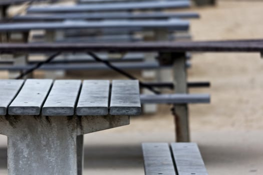 Empty picnic tables, lined up, with selective focus on weathered front table; location is New Jersey shore, Brigantine and Ventana area; 