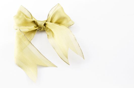 Metallic ribbon as beautiful bow placed on white, rectangular gift box background with copy space on right;