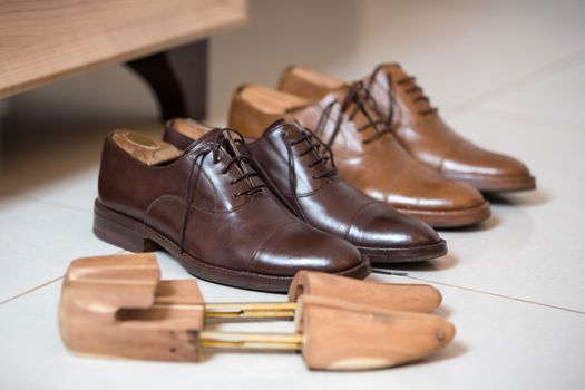 Two pairs of brown handmade classic men's shoes  with a shoe pads and stretchers inside and beside the shoes