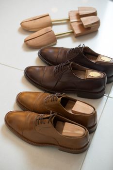 Two pairs of brown handmade classic men's shoes  with a shoe pads and stretchers inside and beside the shoes