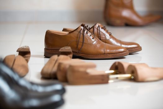 Pair of brown handmade classic men's shoes  with a shoe pads and stretchers inside and beside the shoes