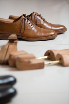 Pair of brown handmade classic men's shoes  with a shoe pads and stretchers inside and beside the shoes