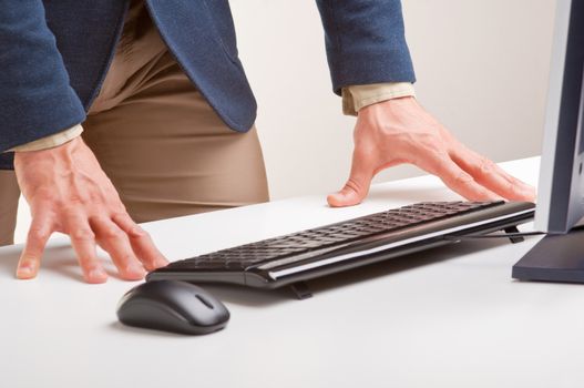 Man standing and looking at a computer screen with his hands on the desk