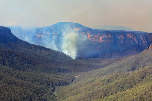 A bushfire burns in the Grose Valley near Blackheath in the Blue Mountains, Australia. Rugged and difficult terrain with only a few access points has hampered its extinguishment. Has so far burned 496ha and has a 66km fire edge. Orange smoke has drifted hundreds of klms  (October 2013)