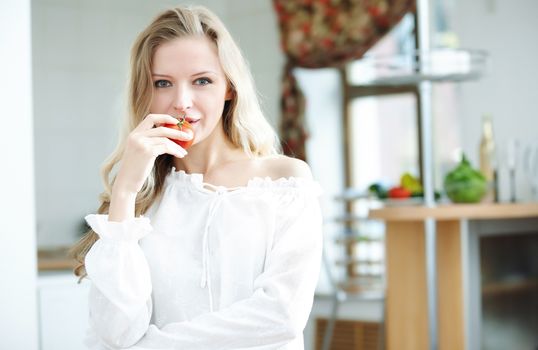 Blond lady with ripe tomato at the kitchen