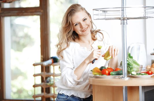 Smiling lady eating vegetables at kitchen