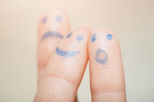 Three fingers with painting of various emotional faces