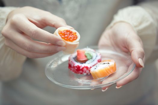Human hands holding plate with sushi