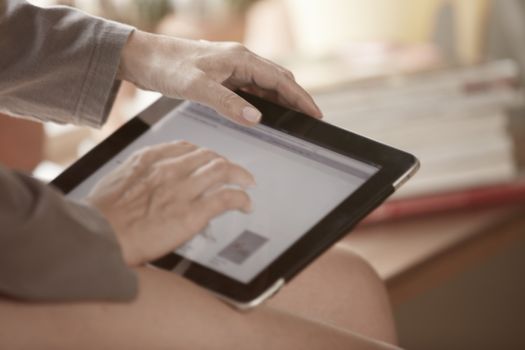 Hands of woman using digital tablet at home