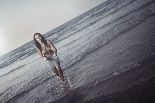 Young adult woman splashing at the evening beach