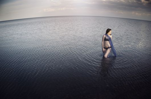 Woman in the sea before the storm. Horizontal photo. Artistic horizon distortion added due to the wide angle lens