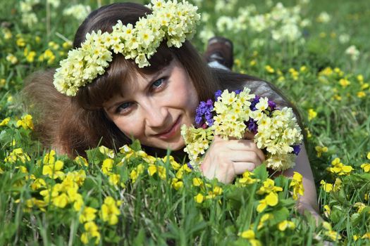 Girl with a wreath and a bouquet of spring on the lawn