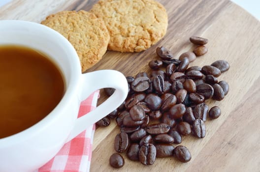 Coffee beans and cup with cookies on wooden background