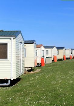 Scenic view of row of caravans in trailer park with blue sky background.