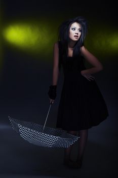 Brunette lady holding umbrella on a dark background. Artistic darkness and colors added