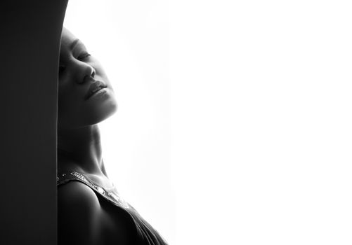 Passionate lady indoors on a white background. Black and white photo with artistic darkness and shadows
