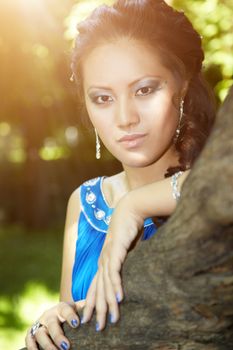 Beautiful Asian lady outdoors near the tree under the sunlight. Natural colors added