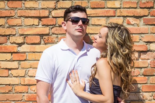 Young couple portrait in front of the brick wall background